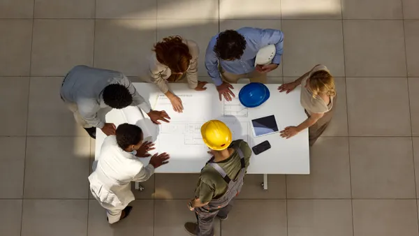 An aerial view of a group of construction professionals having a meeting over drawings.