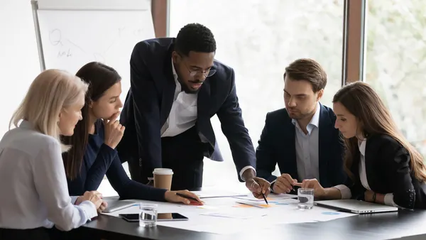 Confident african American male boss work cooperate with diverse team at office briefing
