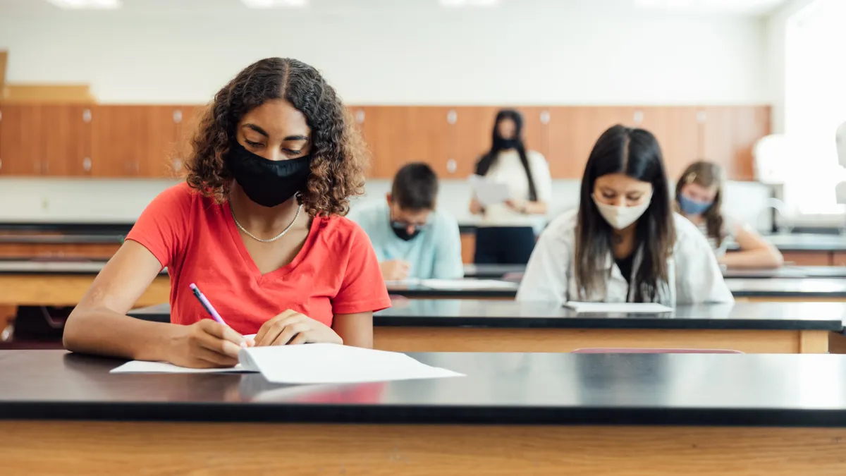 High school students and teenagers go back to school in the classroom at their high school. They are required to wear face masks and practice social distancing during the COVID-19 pandemic.