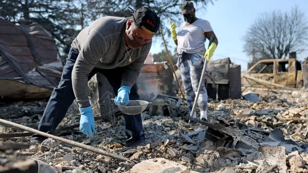 people sift through debris from a fire