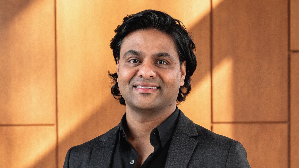 Sanket Shah stands in front of a wood wall.