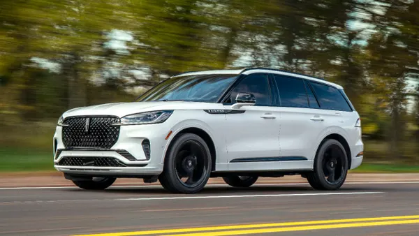 A white 2025 Lincoln Aviator SUV on road with tress and greenery in the background.