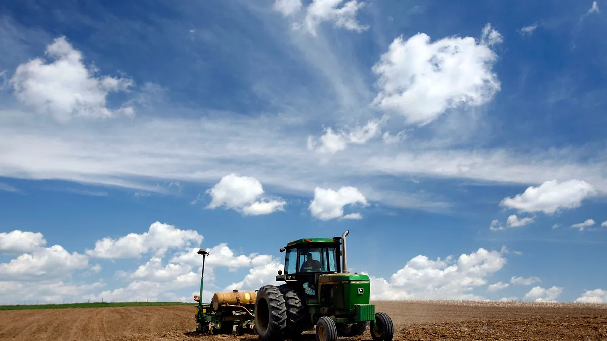 A farmer pulls a corn planter behind his John Deere tractor.