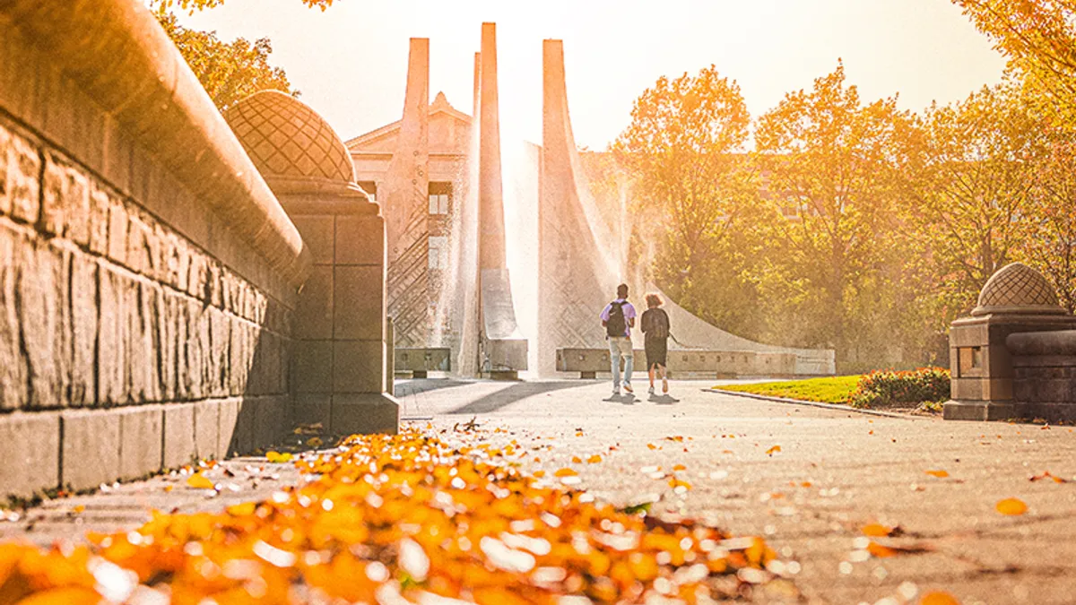 Two students walking on a college campus in the fall.