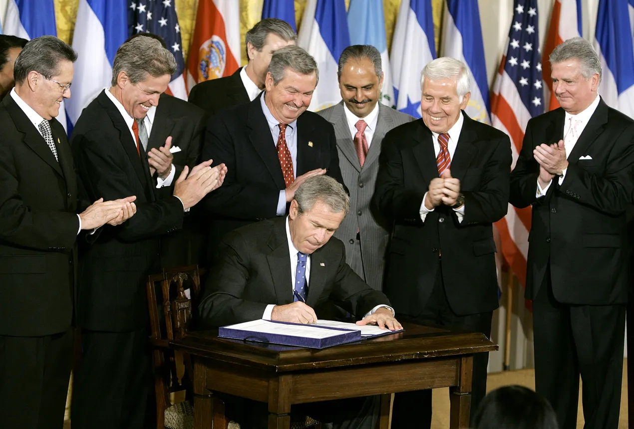 President George W. Bush signs the Central American Free Trade Agreement at the White House surrounded by representatives Central America and U.S. senators and congresspeople.