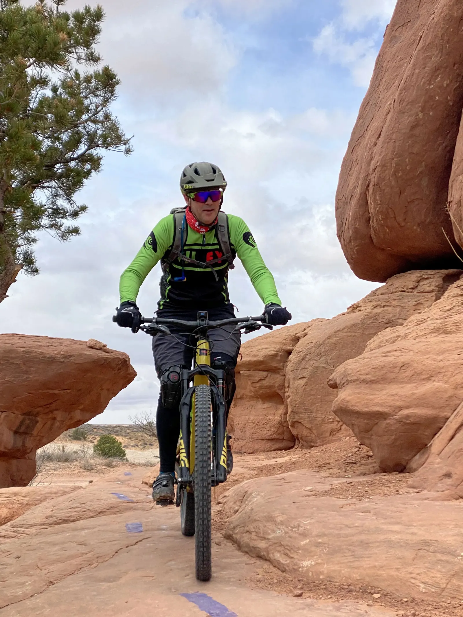 A man in sportswear rides a bicycle on a stony terrain.