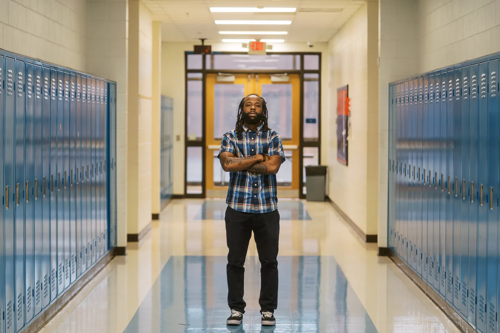 A person stands in the middle of a school hallway.