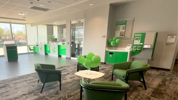 The interior of an Associated Bank branch shows chair seating, green balloons on table, and other elements of the bank branch.