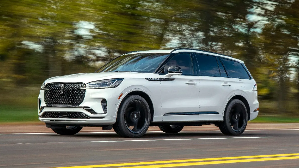 A white 2025 Lincoln Aviator SUV on road with tress and greenery in the background.