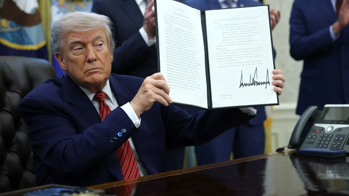 President Donald Trump holds up a signed executive order in the Oval Office of the White House