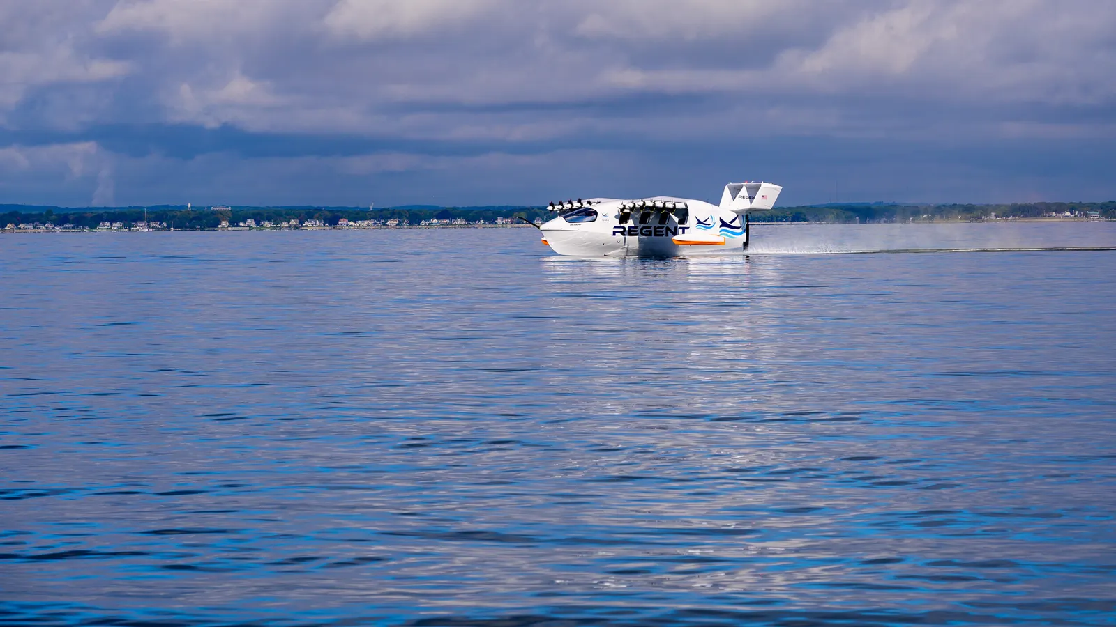 A white vessel with many small propellers on two wings floats on a body of water.