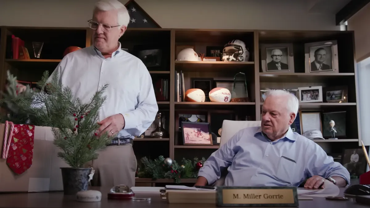 Two men behind a desk with Christmas decorations on it.