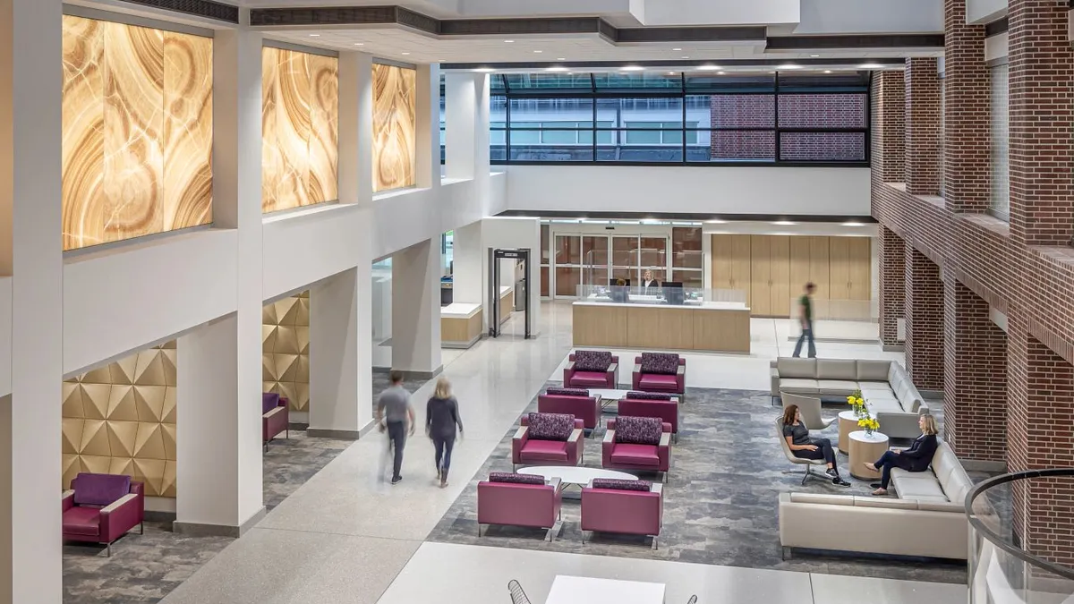 A shot from an upper floor into an open area of a hospital, with couches on the bottom, and open areas that look into the upper levels.