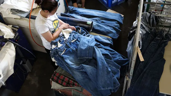 A person checks pockets of a stack of jeans in a room.