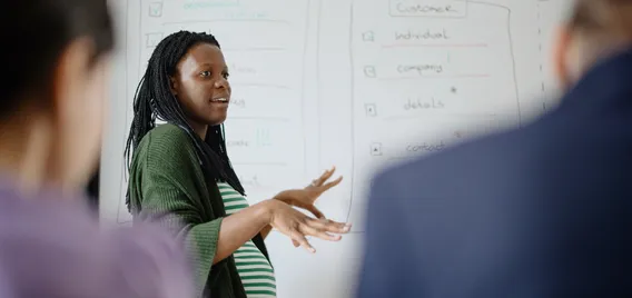 A pregnant worker gives a presentation at the office.