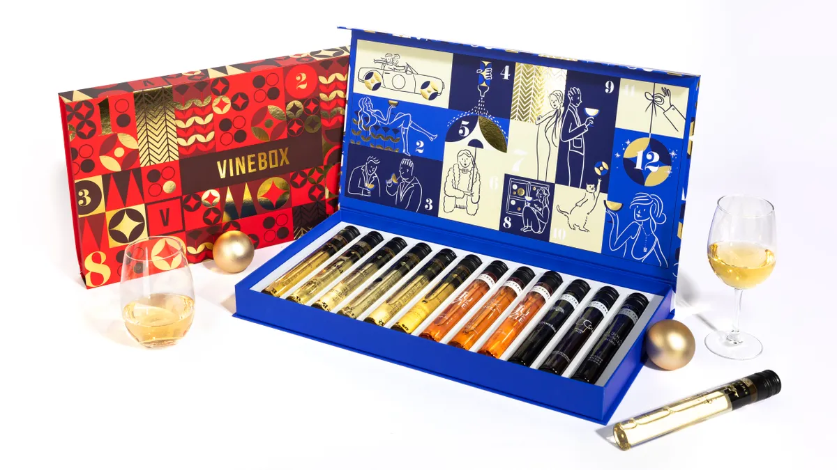 A blue, open "advent calendar" box displays 12 vials of wine inside and sits next to a similar red box.