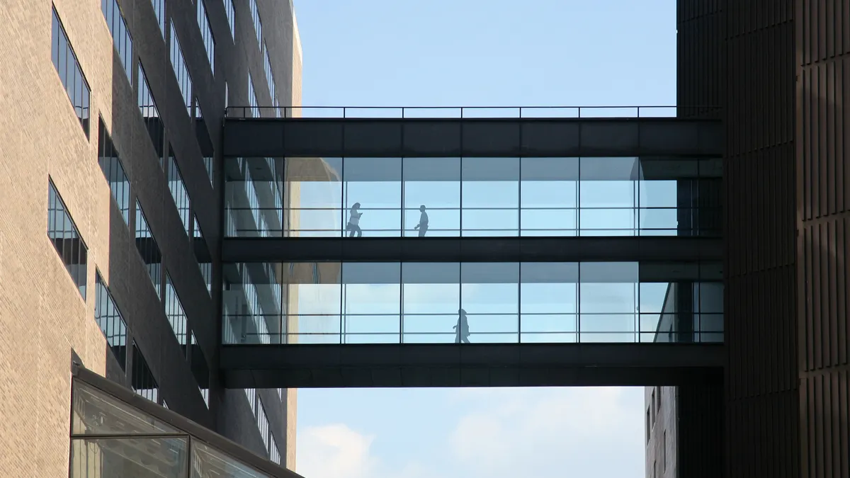 Silhouette of People walking on a bridge between two buildings