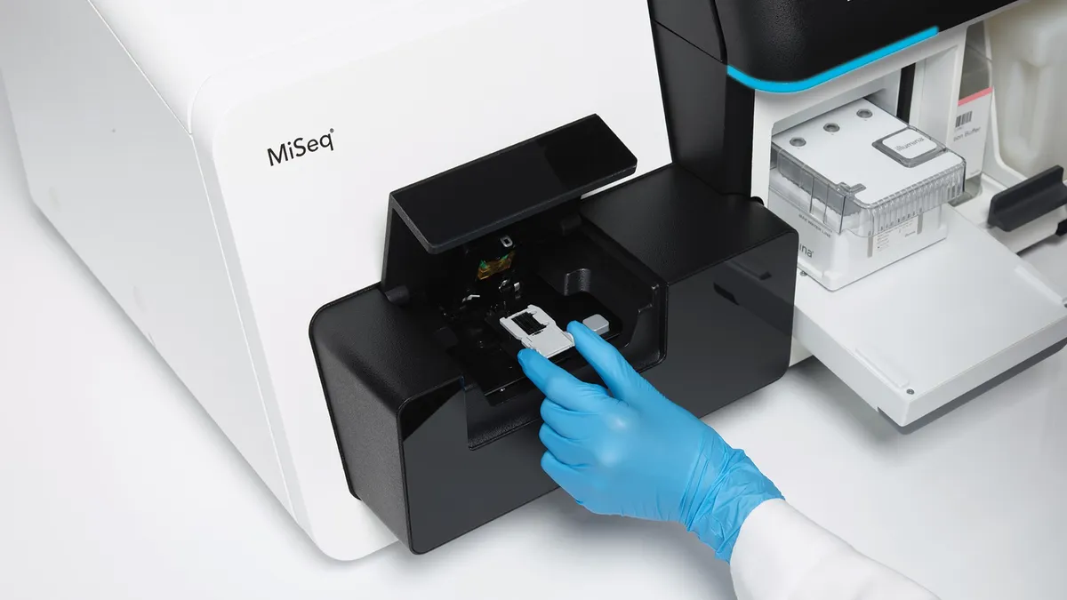 A scientist's hand using an Illumina MiSeq gene sequencing machine