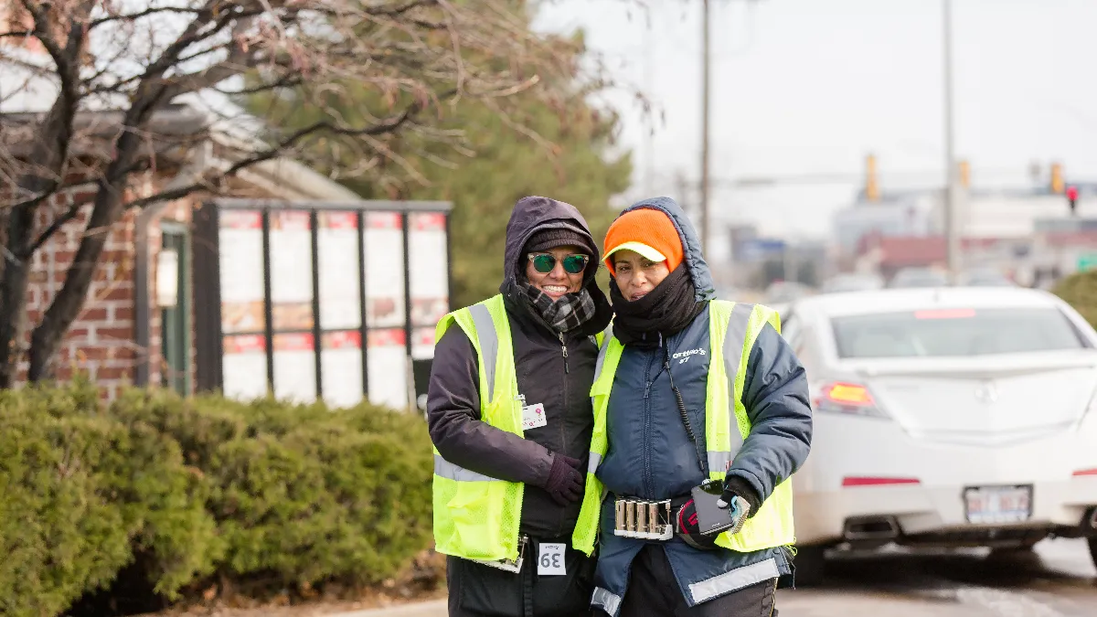 An image of two employees of Portillo's at the drive-thru.