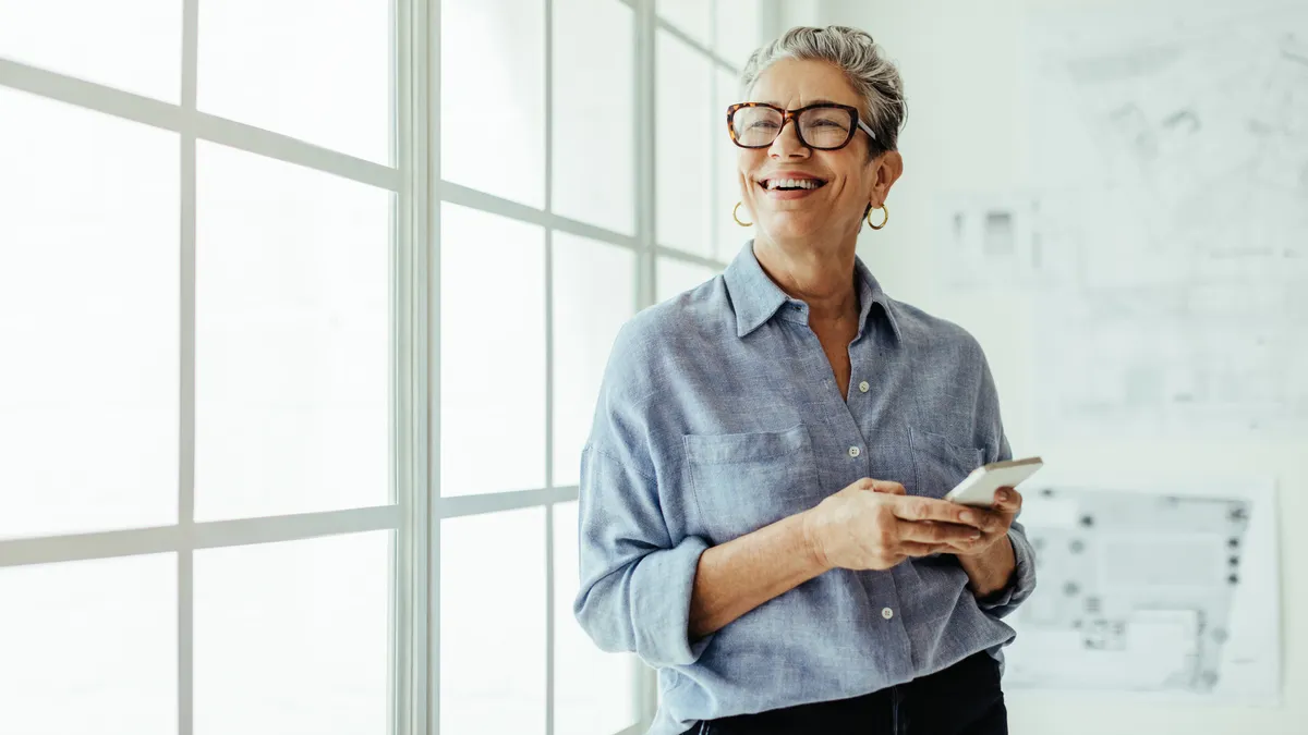 A worker with grey hair smiles in a well-lit office