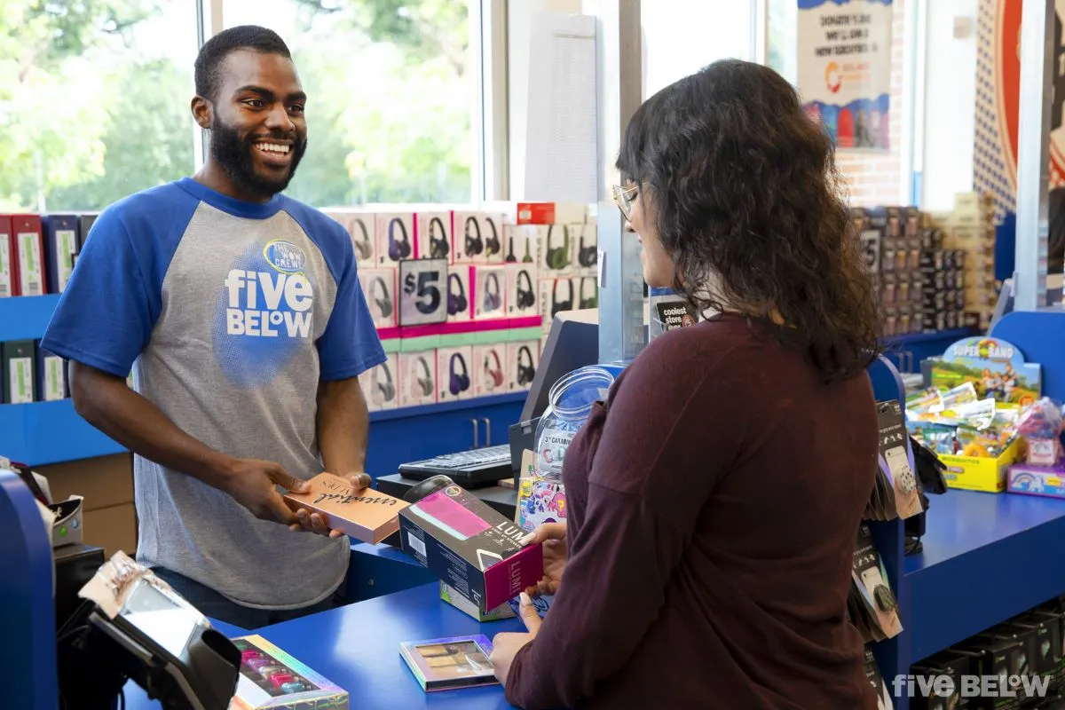 A Five Below employee assists a customer at the checkout counter