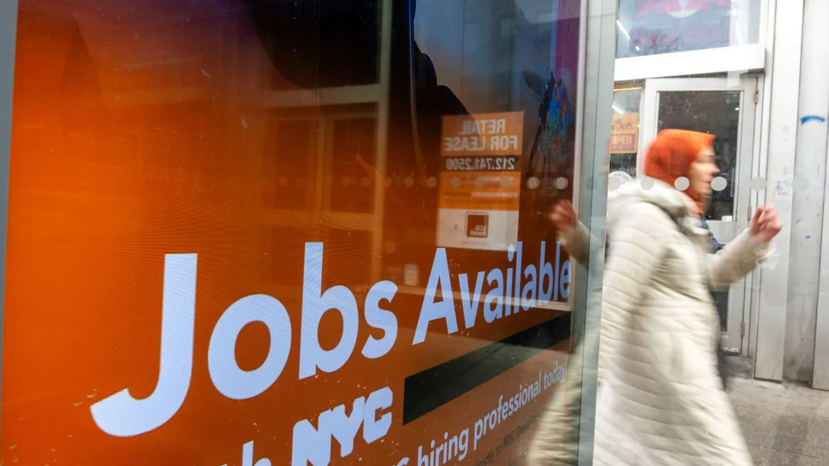 A person walks past an advertisement that says "jobs available."