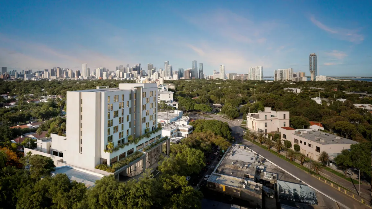 Aerial picture of a white high-rise residential building with the Miami skyline in the background.