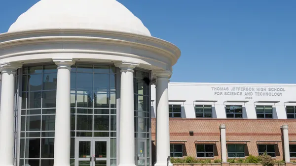 A school building is seen against a blue sky. On the building are the words Thomas Jefferson High School for Science and Technology 6560