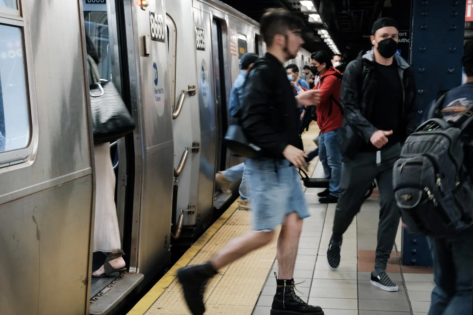 Many people exit and enter a silver New York City subway trains at a Manhattan underground station.