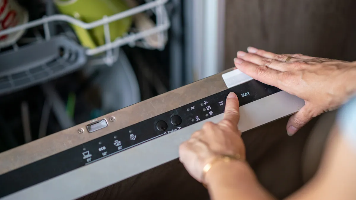 Person operating a residential dishwasher machine