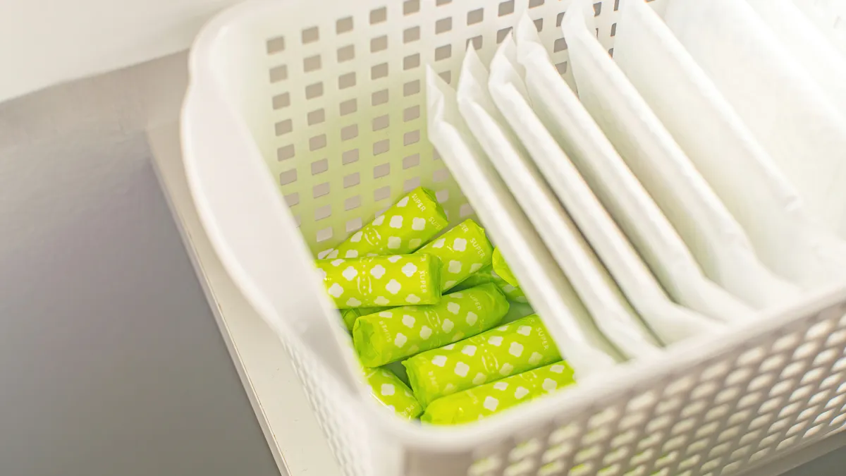 Feminine hygiene products: tampons and pads in a basket in the locker room.