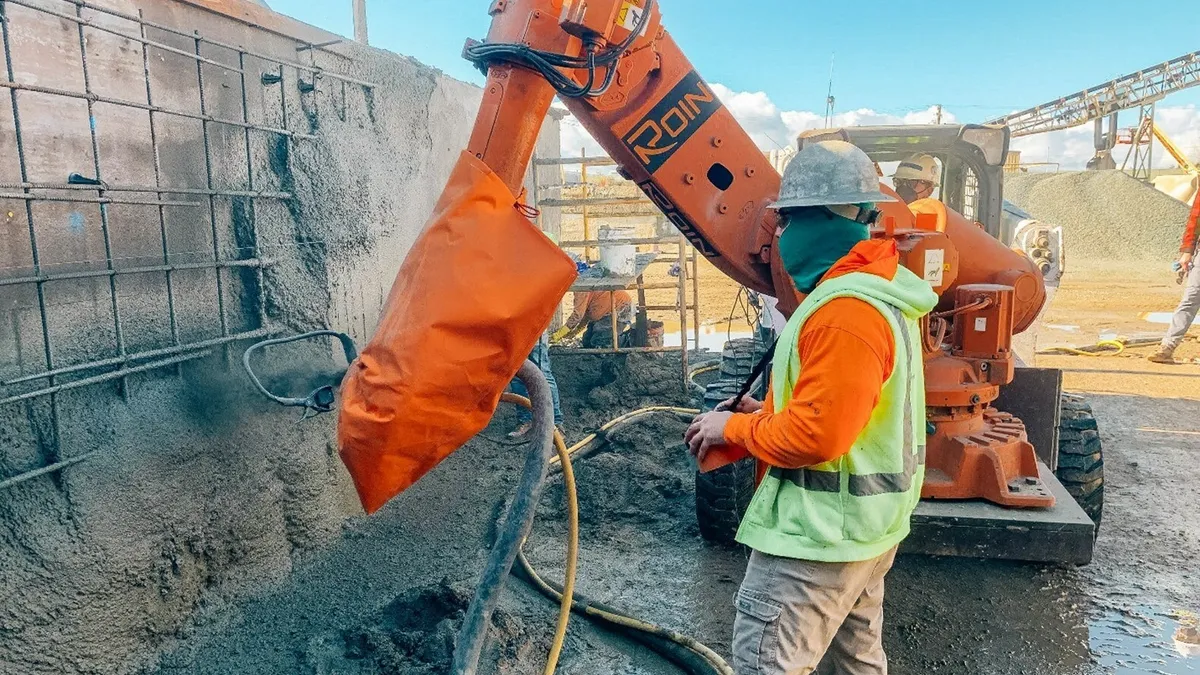 Roin's technology at work on a jobsite with a construction worker in front of it. The robot and human are in a trench.