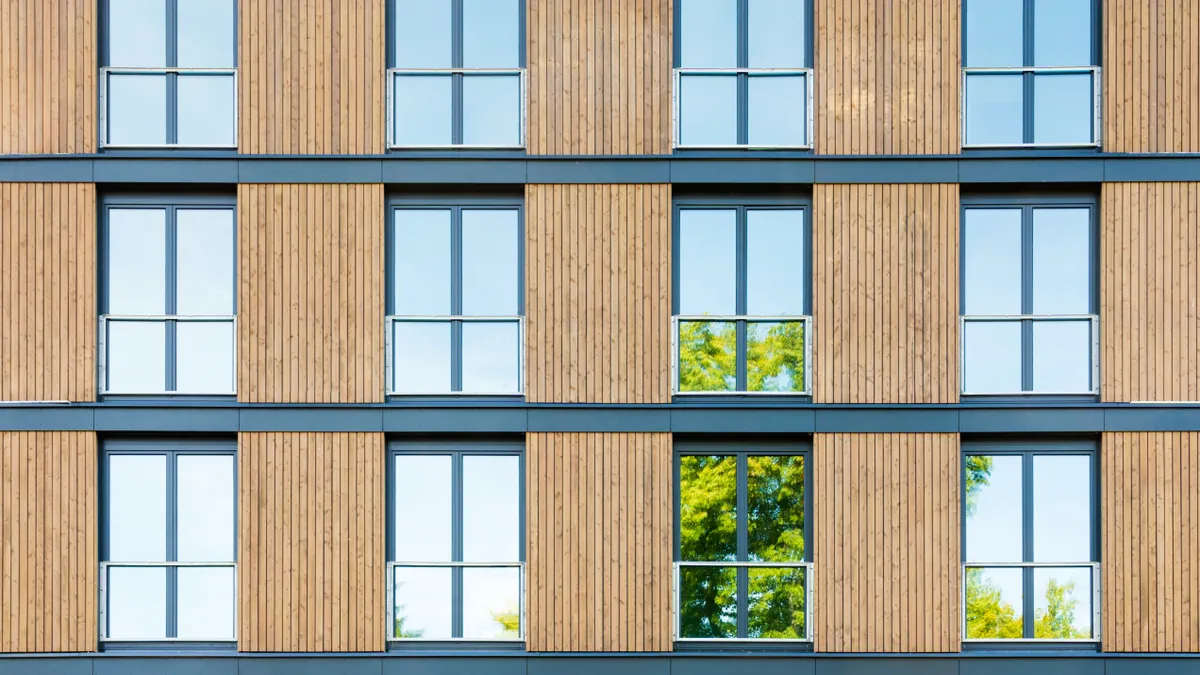 The facade of a building with a tree emerging from the bottom.