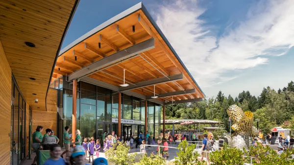 A wooden building looms in the background amid a crowd rolling through the area.