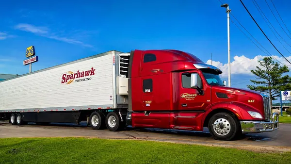 A Sparhawk Trucking tractor-trailer next to a truck wash sign.