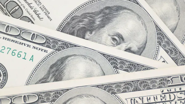 A stack of US one hundred dollar bills is spread out on a table. 