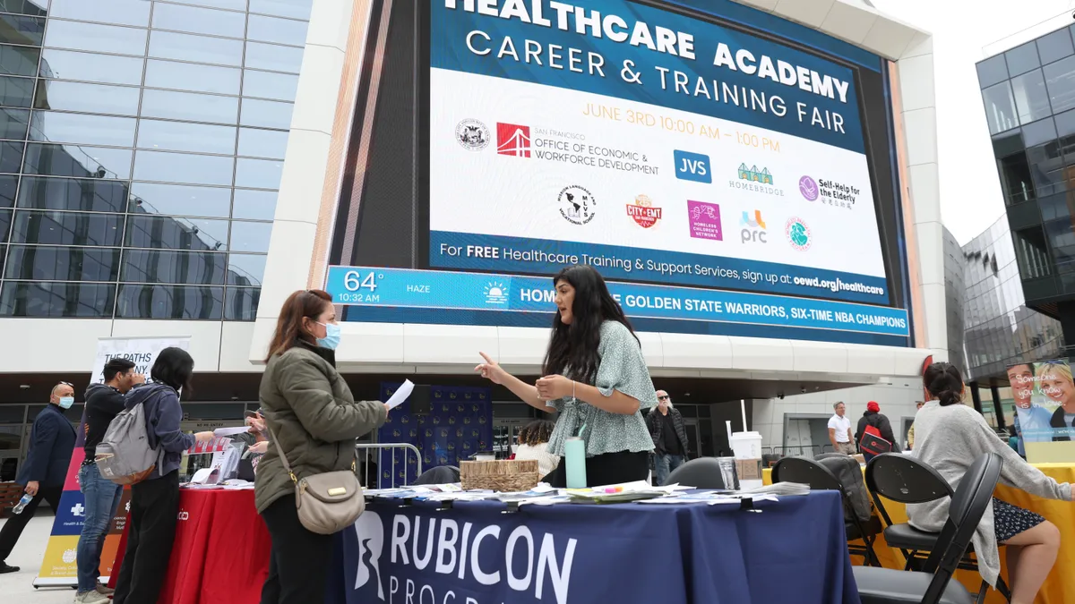 Job seeker stands across from a recruiter at an outdoor job fair.