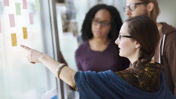 Creative colleagues reviewing ideas on wall in studio office stock photo