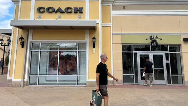 People walk in front of a Coach outlet store.