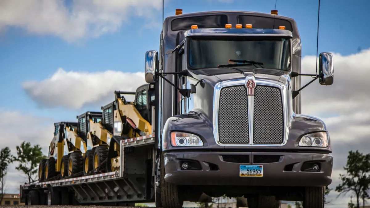 An E.W. Wylie flatbed truck carrying construction equipment.