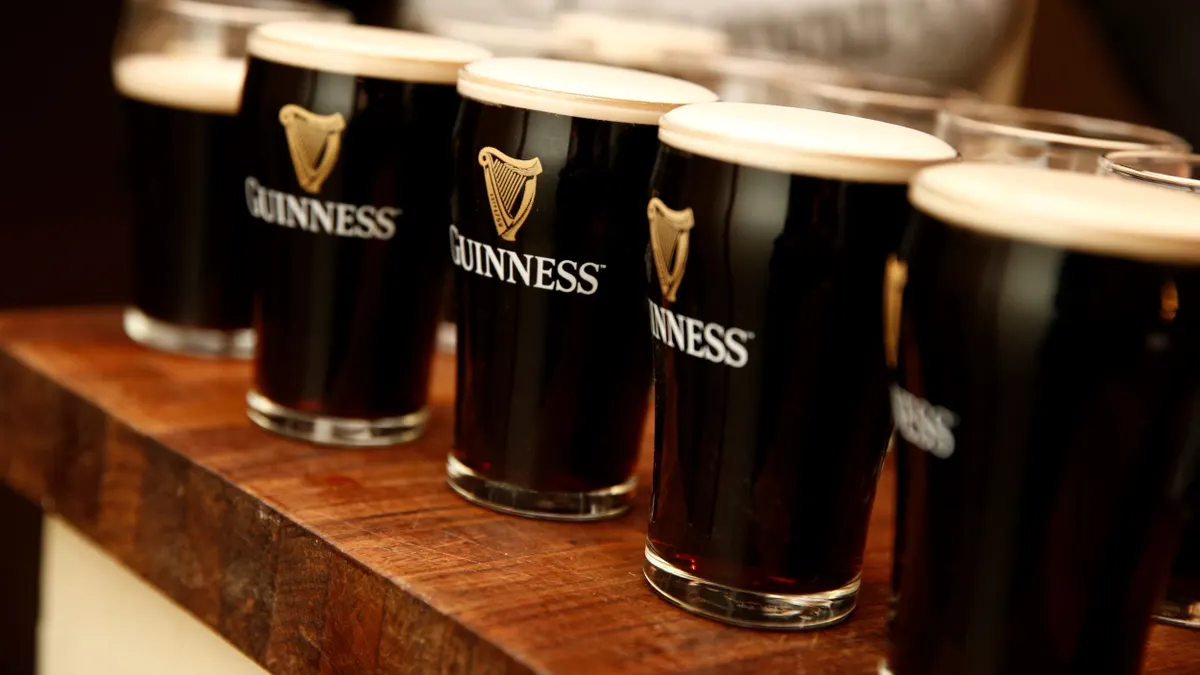 Pint glasses filled with Guinness beer are displayed on a wooden table.
