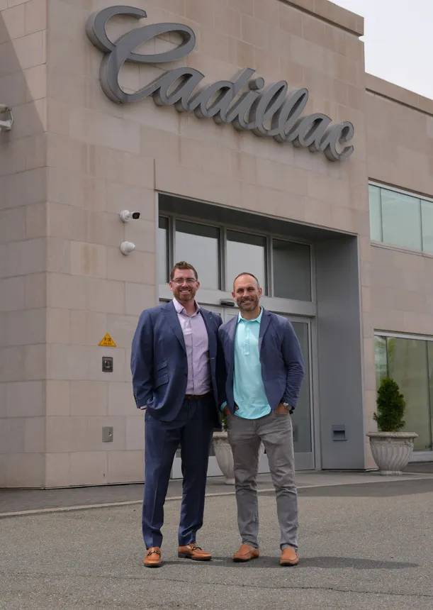 Two men in front of Englewood Cliffs Cadillac in New Jersey.