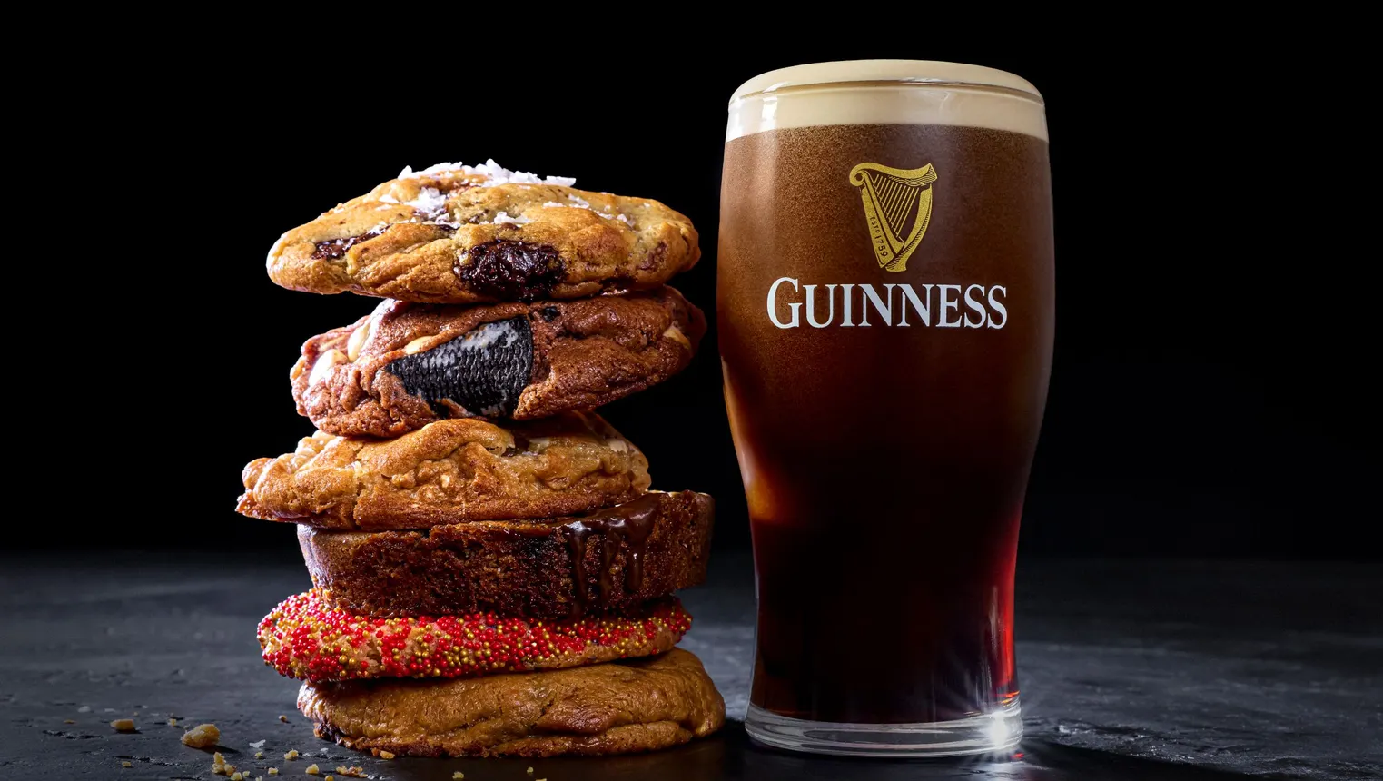 A stack of cookies is next to a pint of Guinness in a glass.