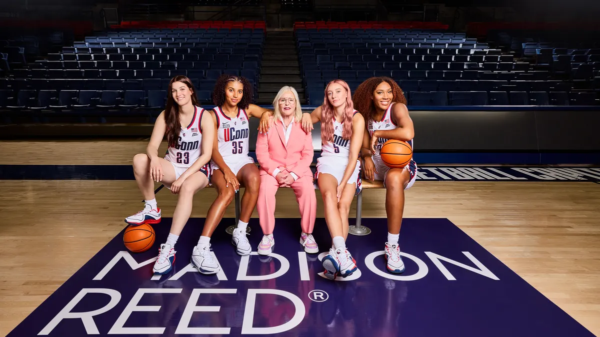 Madison Reed founder Amy Errett sits at the center of a group of four University of Connecticut women's basketball players.