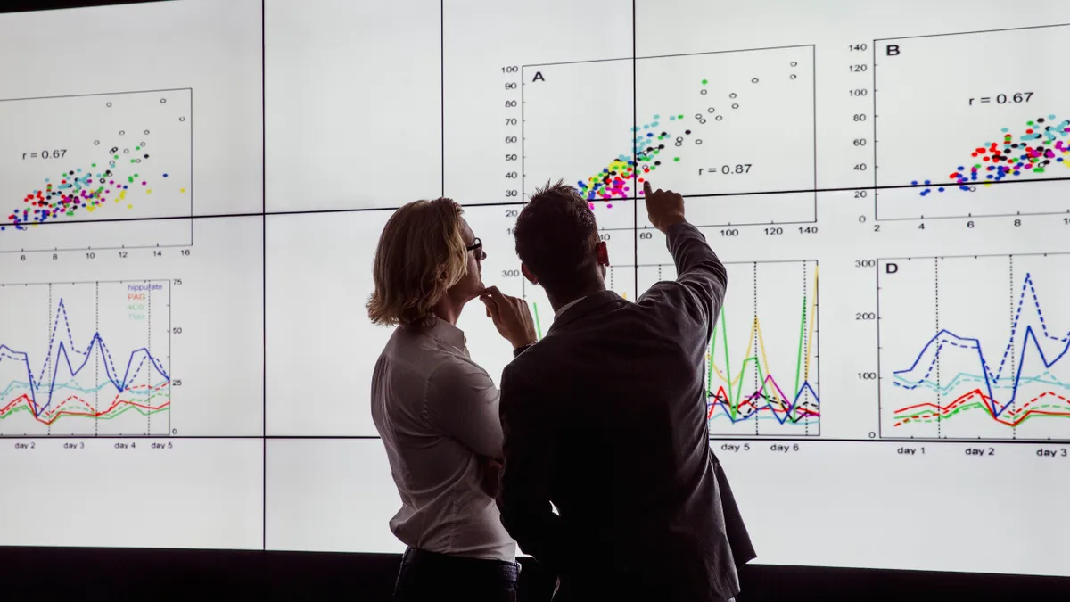 Business men in a dark room standing in front of a large data display