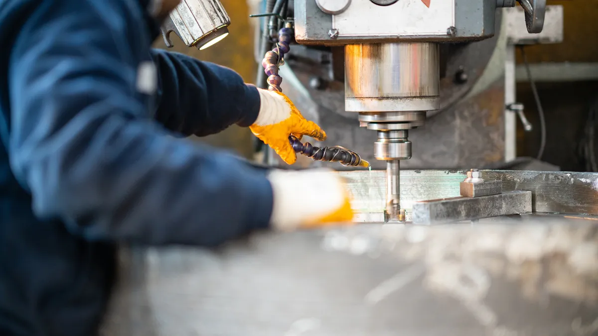 A worker in a factory uses a milling machine