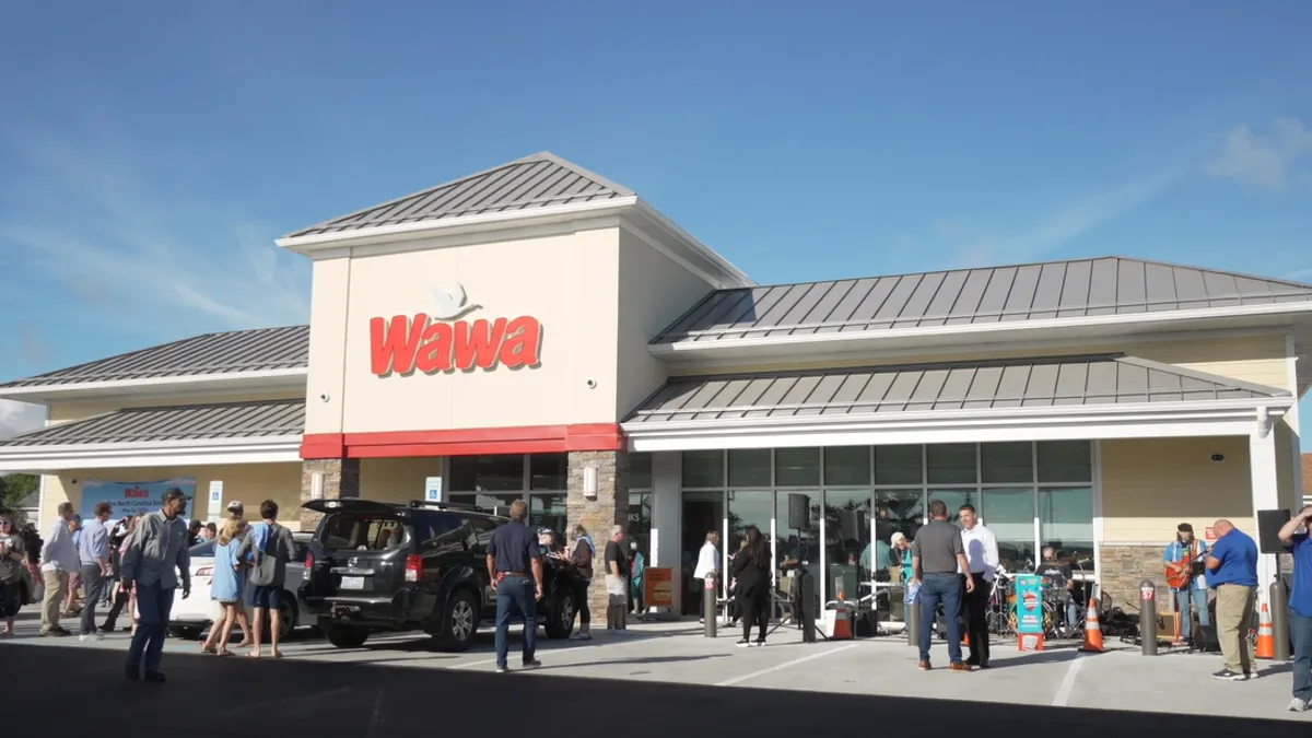 A photo of the exterior of a retail store with a lot of people walking around it. The sign on the store says Wawa.