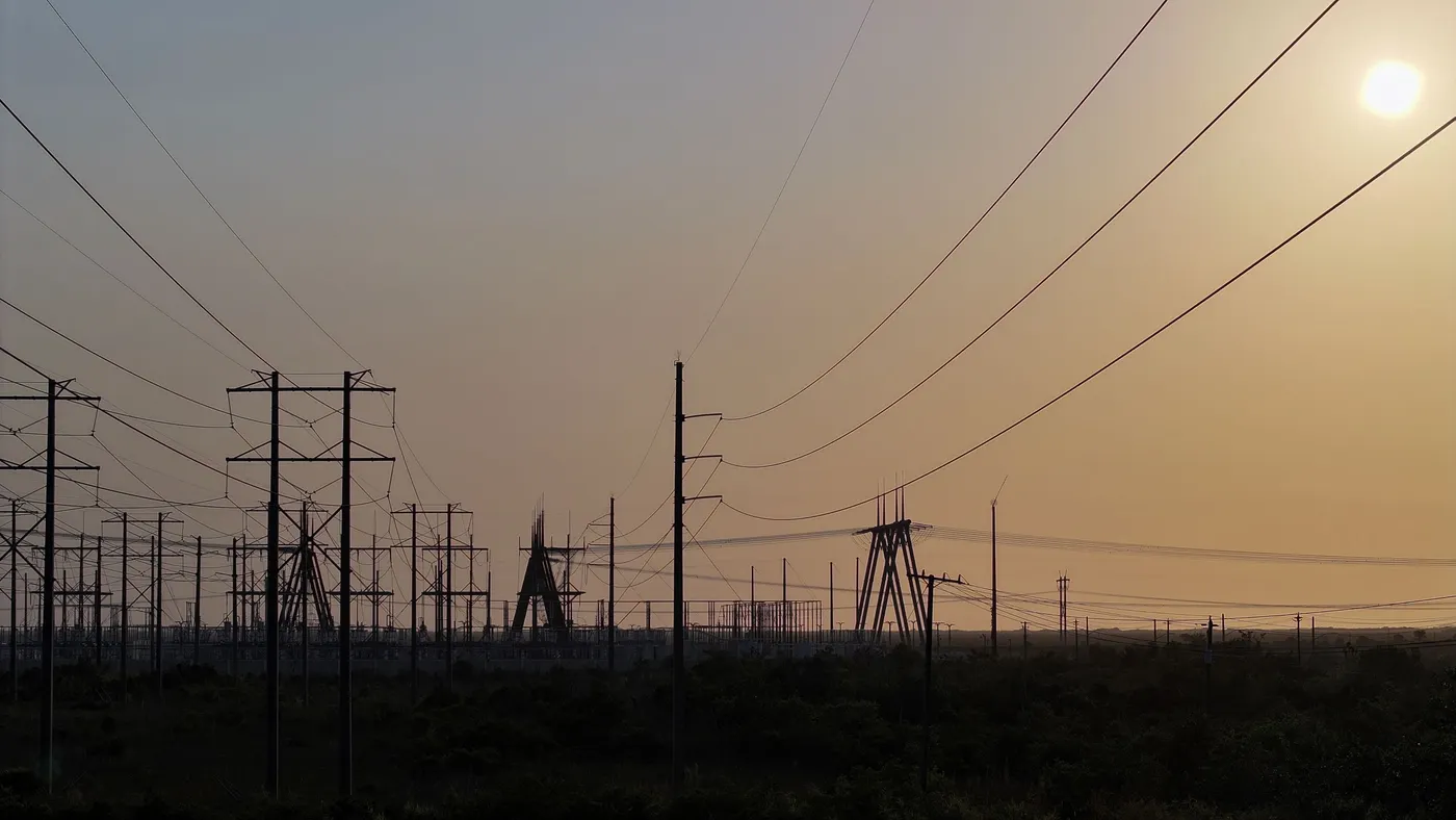 High voltage power lines seen in silhouette at sunset