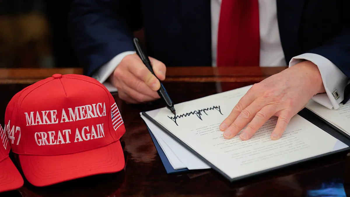 MAGA hats sit next to an executive order being signed by President Donald Trump