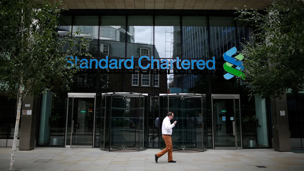 A man smokes outside a Standard Chartered bank location.